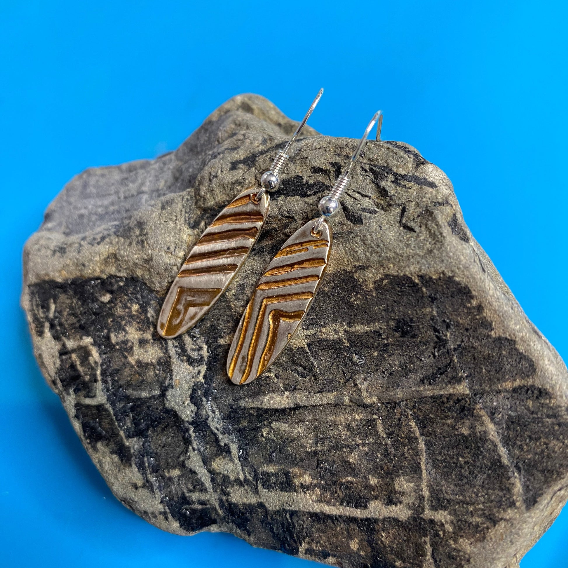 Pair of earrings on a rock with a blue background