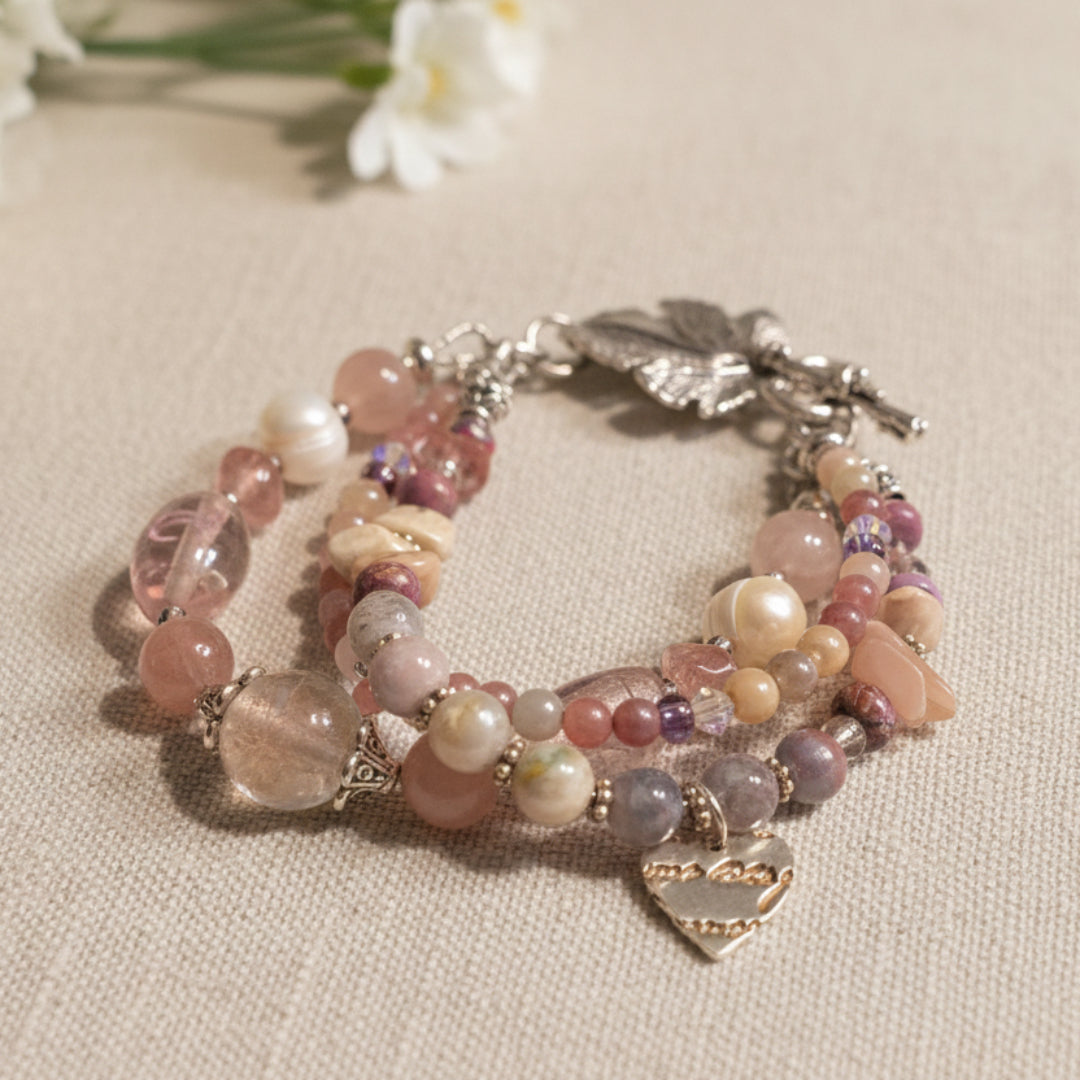 Multicolored beaded bracelet with leaf and butterfly charms on a soft linen background.