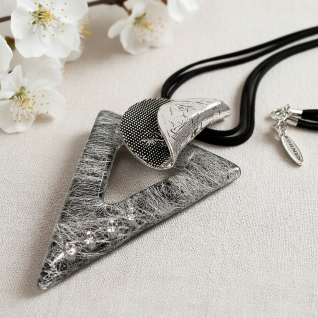 Triangular shaped necklace with geometric design on a black leather cord. Designed by Jacqueline Kent and sold by Arlana Exquisite Styles. Statement piece.
