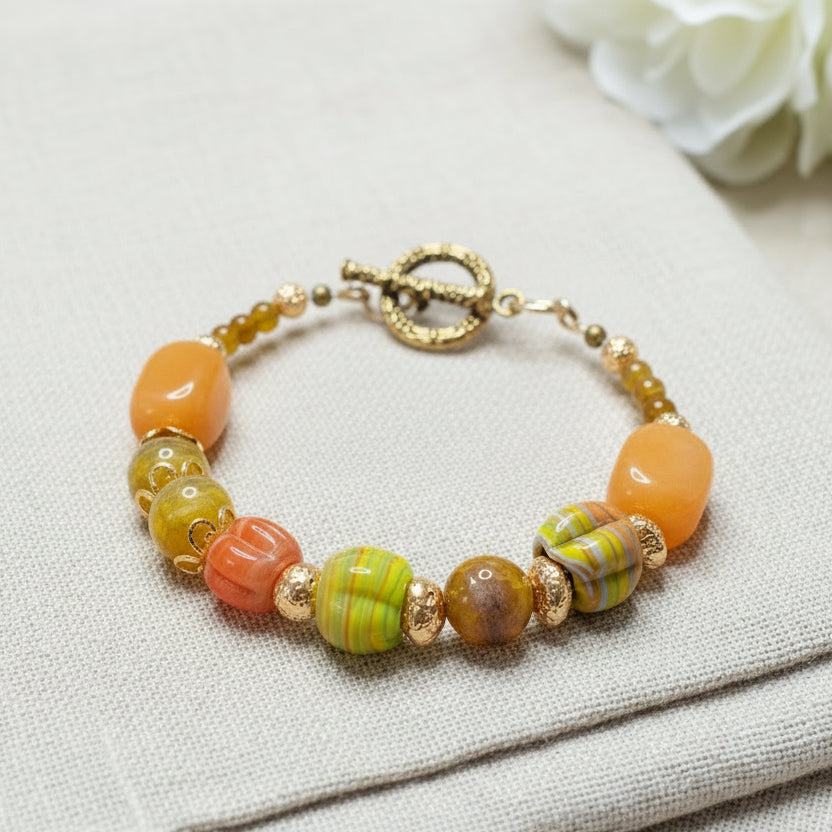 Beaded bracelet with orange and yellow beads on a textured linen background