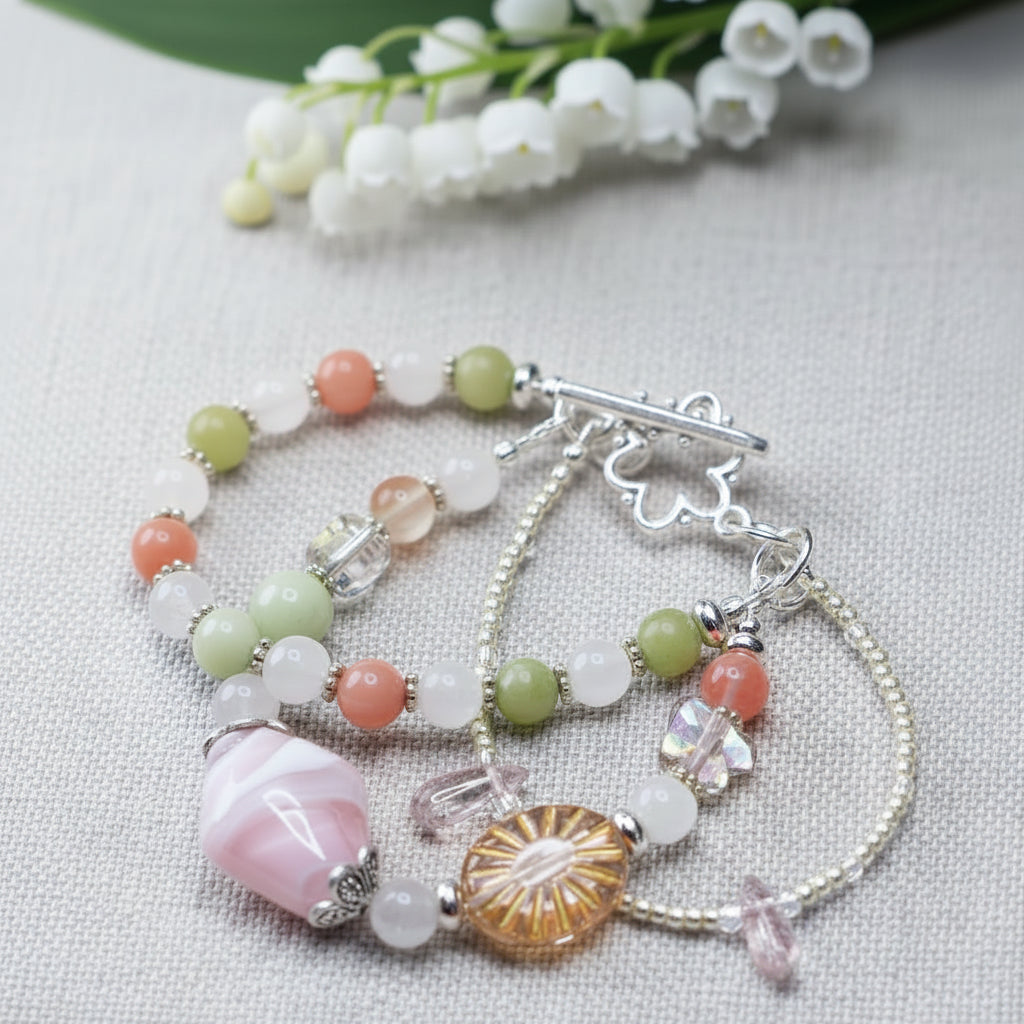 Handbeaded bracelet with various coloured beads and a clasp on a textured background. Represents the month of May.