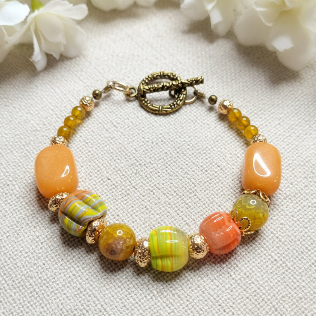 Beaded bracelet in colours of orange, lime green, and gold lava beads on a textured linen background.  Handmade by Arlie Quinn of Arlana Exquisite Styles.
