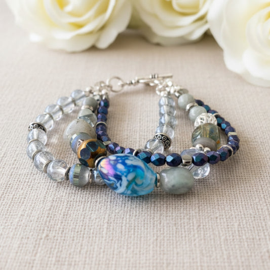 Beaded three strand bracelet featuring lamp work and labradorite beads with silver accents and heart shaped toggle clasp for easy fastening.  Designed and made by Arlie Quinn.